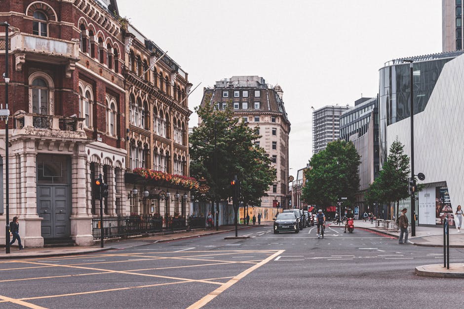 A busy city street scene in Croydon with a mix of historic and modern architecture, featuring a red brick building with decorative white stone accents and flower boxes on the left, along with contempo